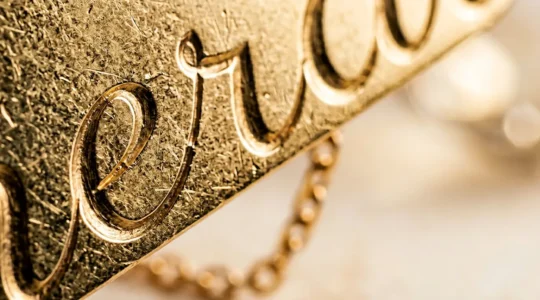 Primo piano ravvicinato di una collana in oro con nome inciso che mostra i dettagli tipografici del carattere